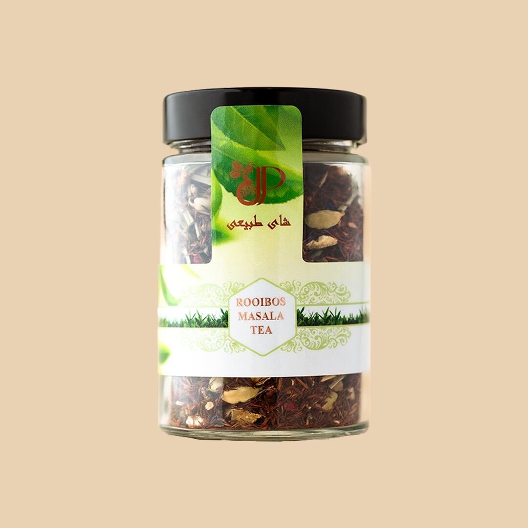 A front-facing glass jar filled with rooibos masala tea, featuring a black screw-top lid and a decorative label with botanical accents on a plain beige backgrou