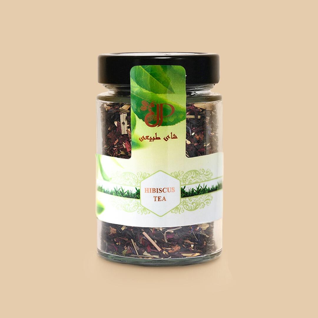 A clear glass jar filled with dried hibiscus tea leaves and herbs, featuring a white and green label with Hibiscus Tea and Arabic text, set against a solid back